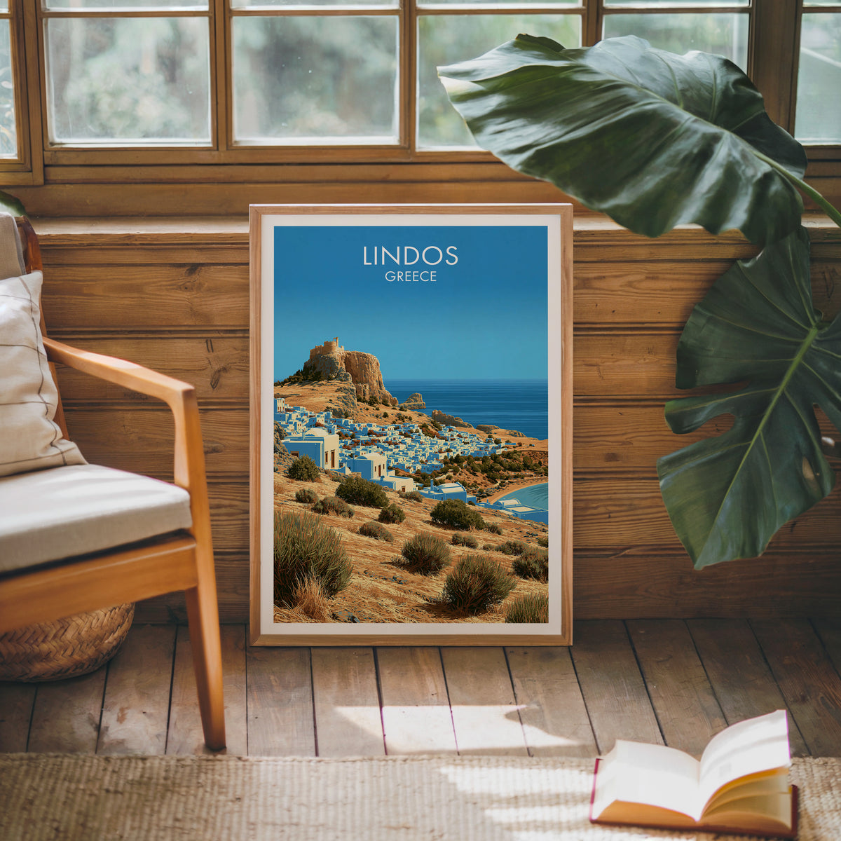 Lindos travel poster, oak frame leaning on a wood-panelled sunroom wall by a mid-century armchair
