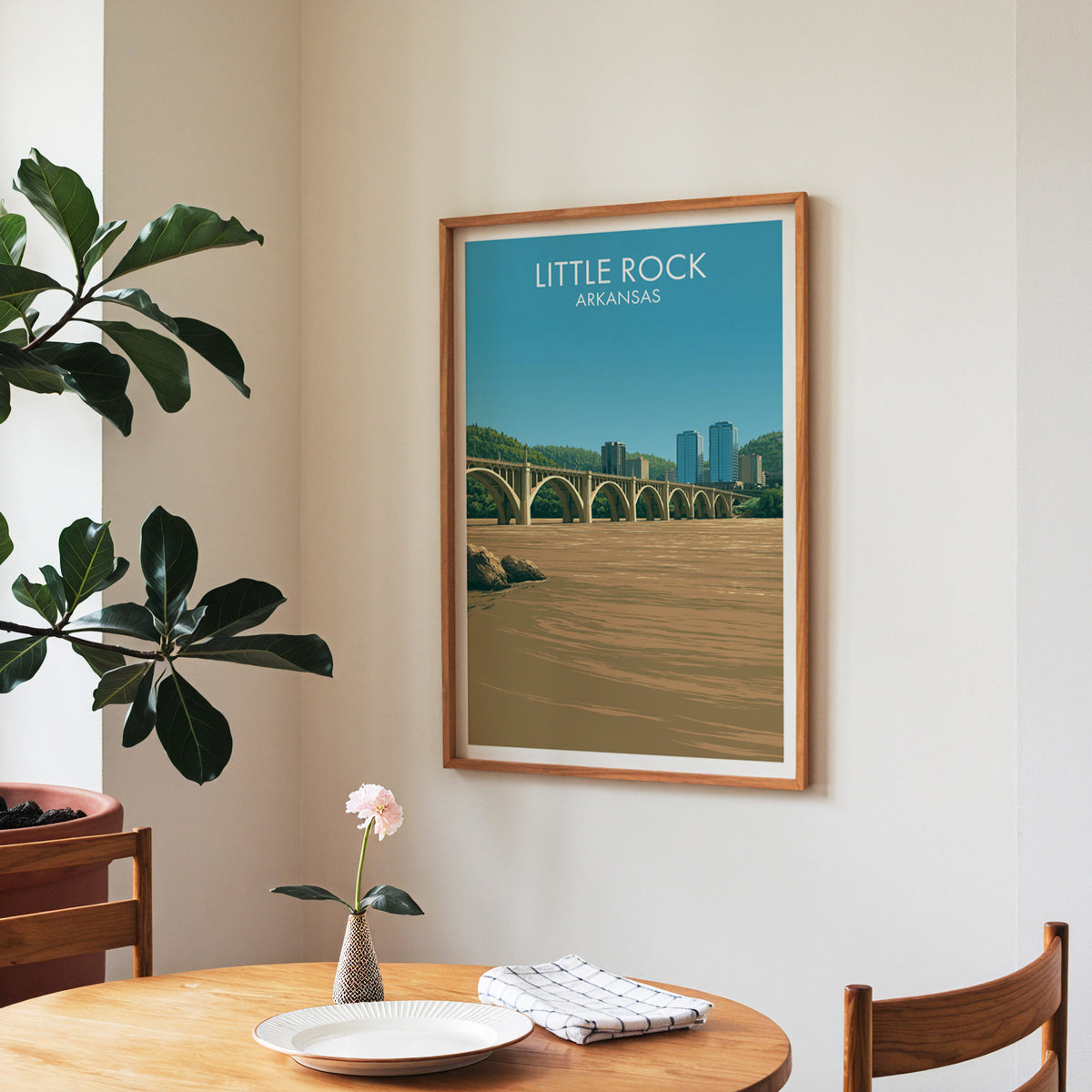 Arkansas river city print in a walnut frame in a dining corner with a round table and checked runner.