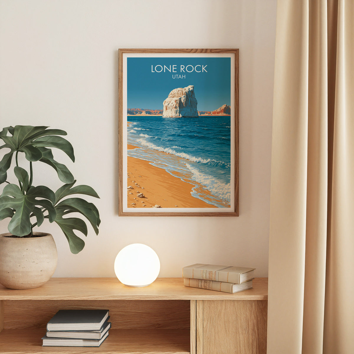 Lake Powell beach print in an oak frame on a beige wall over an oak console with a monstera and globe lamp
