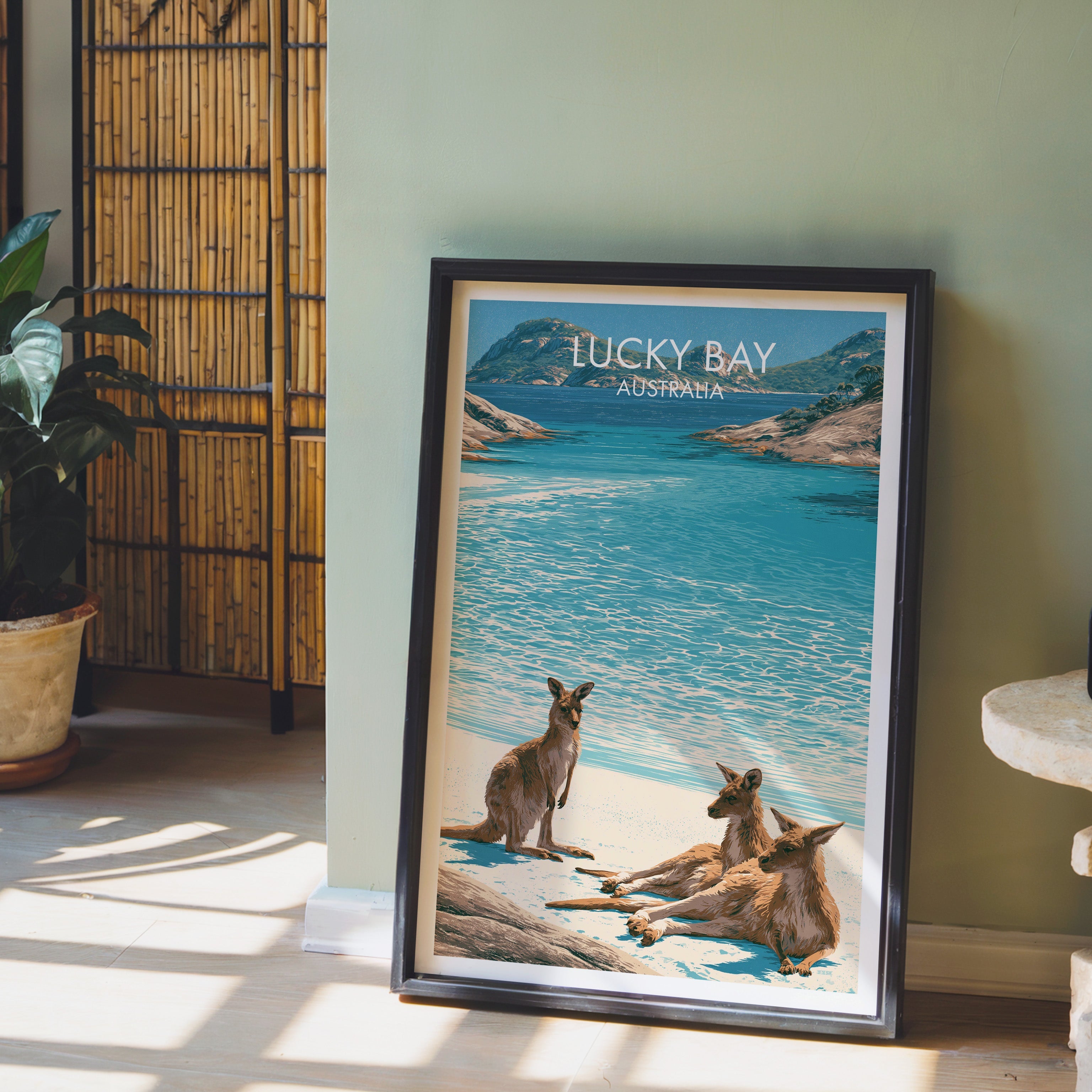 Kangaroo shoreline illustration in a black frame on pale wood floor by a sage wall and bamboo screen