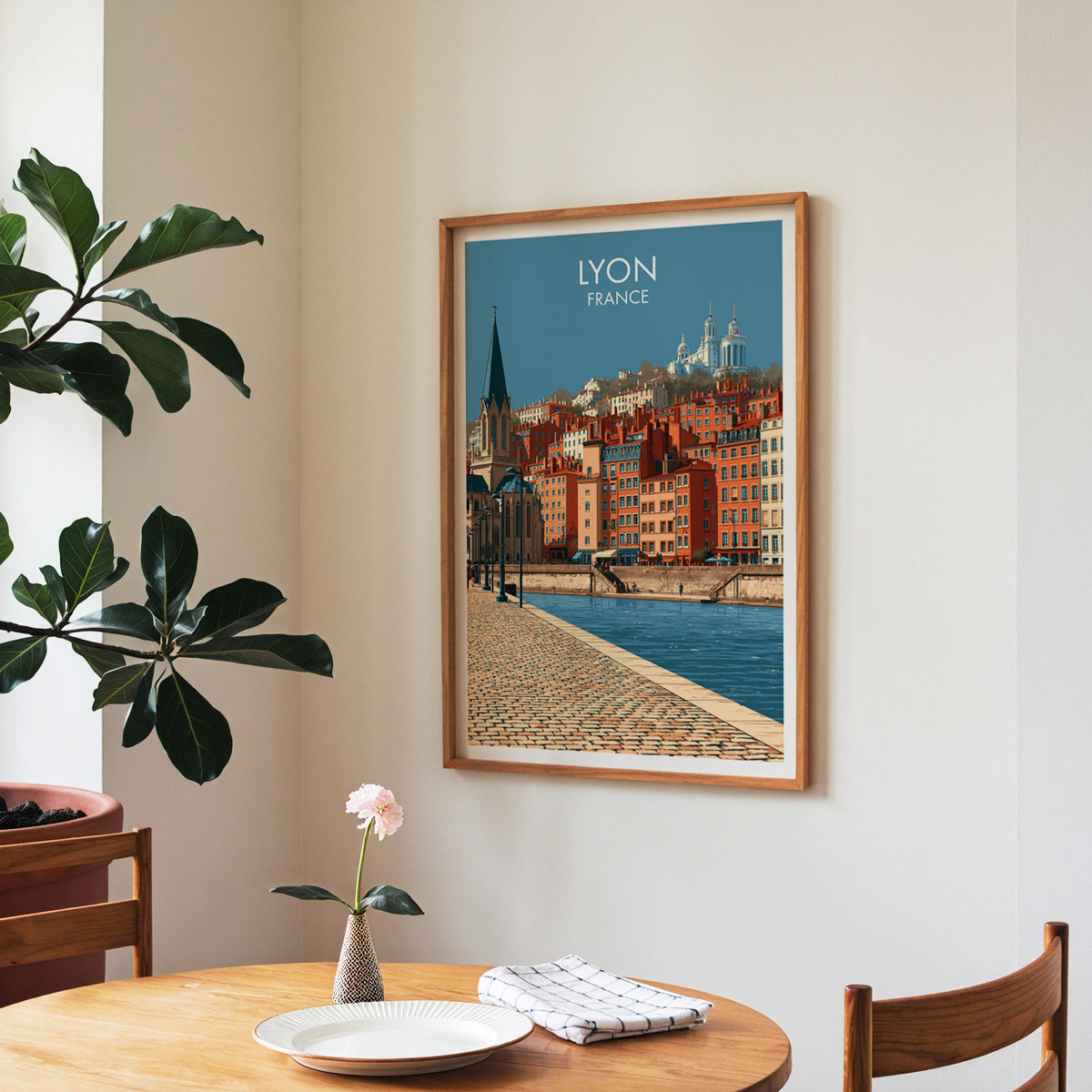 Lyon old town poster, walnut frame in a dining corner above a round table and a fiddle-leaf fig