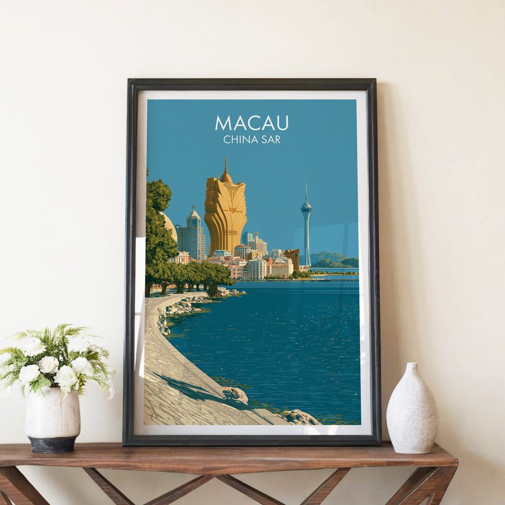 Macau China travel poster in a black frame on a wooden console table with white flowers