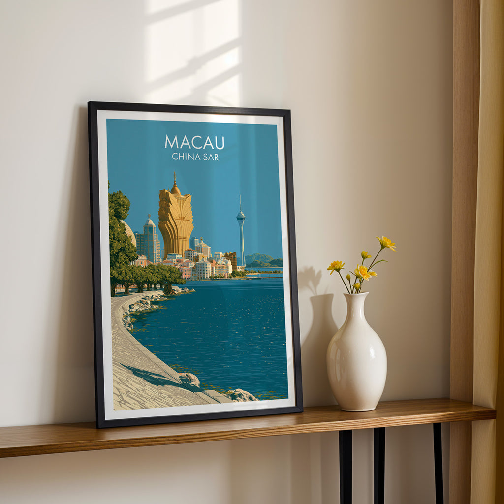Black framed Macau China print on a narrow hallway console in sunlight, styled with yellow flowers