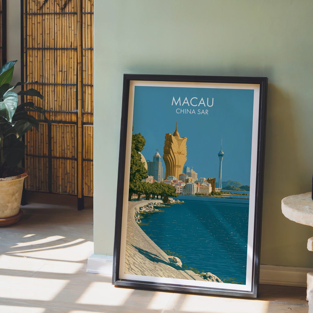 Macau China wall art in a black frame leaning against a sage green wall beside a bamboo screen
