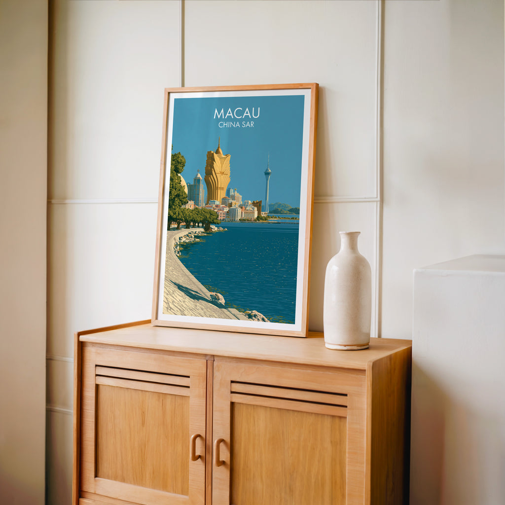 Small Macau China travel poster in an oak frame on a mid-century sideboard with a ceramic vase