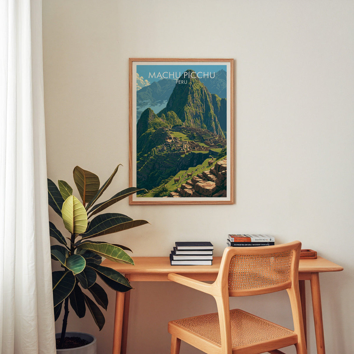 Machu Picchu print in an oak frame above a wooden desk with a cane chair, stacked books and rubber plant