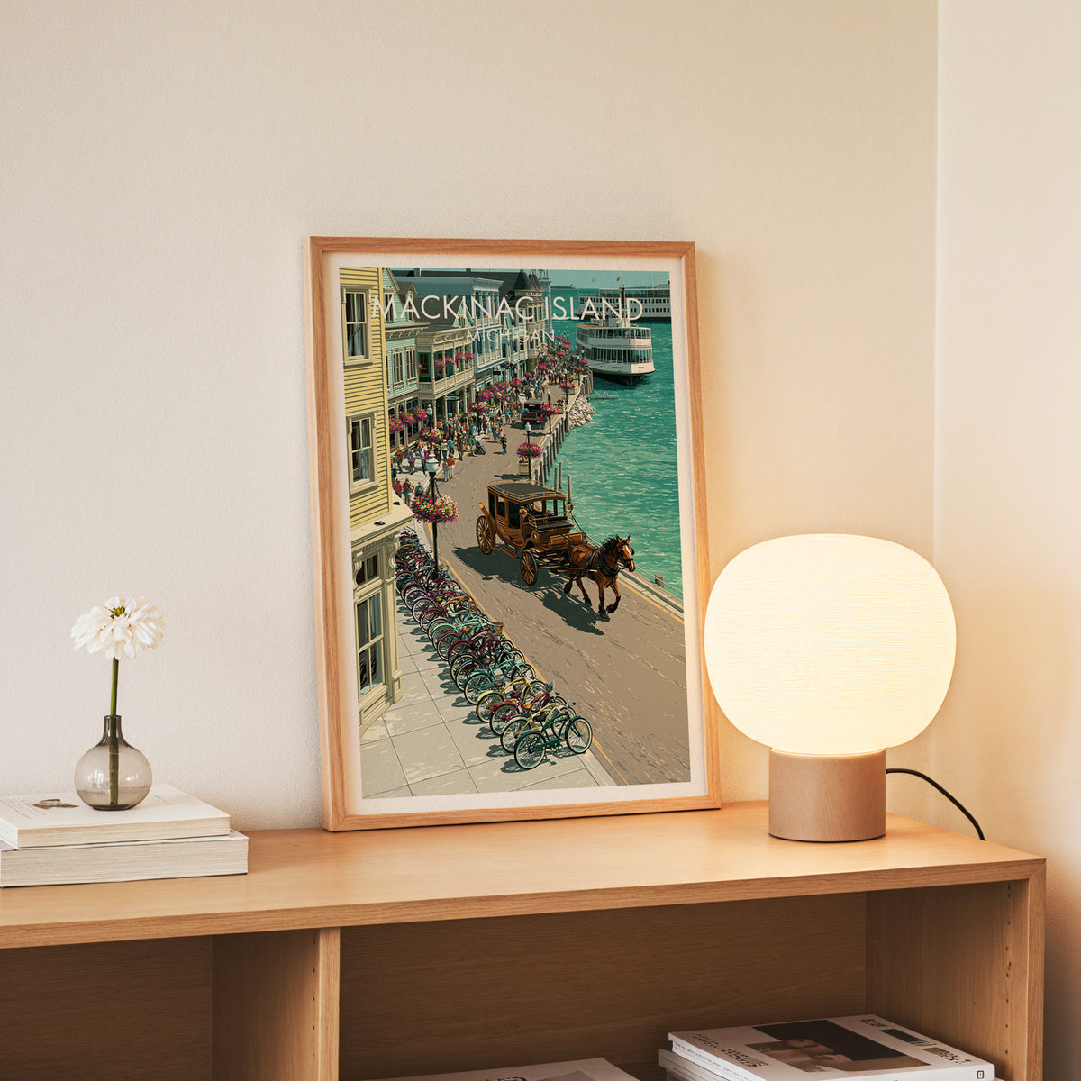 Mackinac Island ferry poster in a slim oak frame standing on a console with daisies in a glass jar.