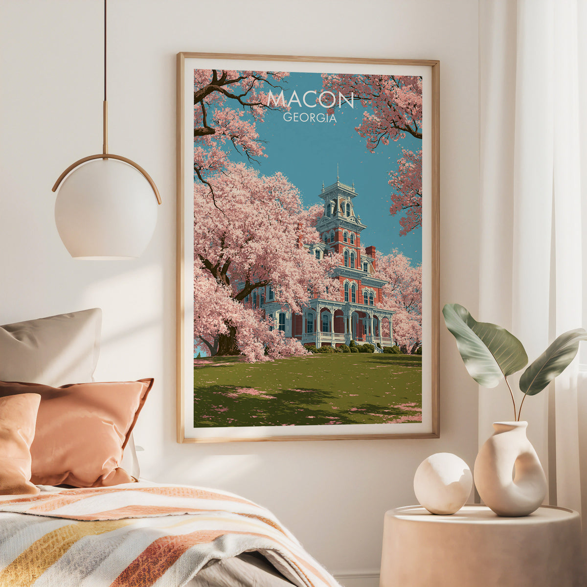 Large oak framed Macon Georgia artwork above a bed with a rust throw and a brass pendant lamp