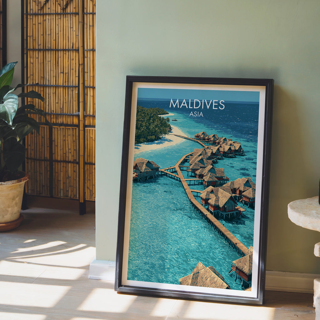 Maldives wall art in a black frame leaning against a sage green wall beside a bamboo screen