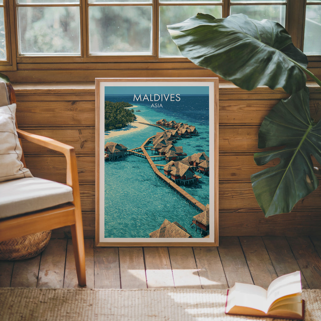 Framed Maldives poster leaning against a timber cabin wall with monstera leaves and an open book