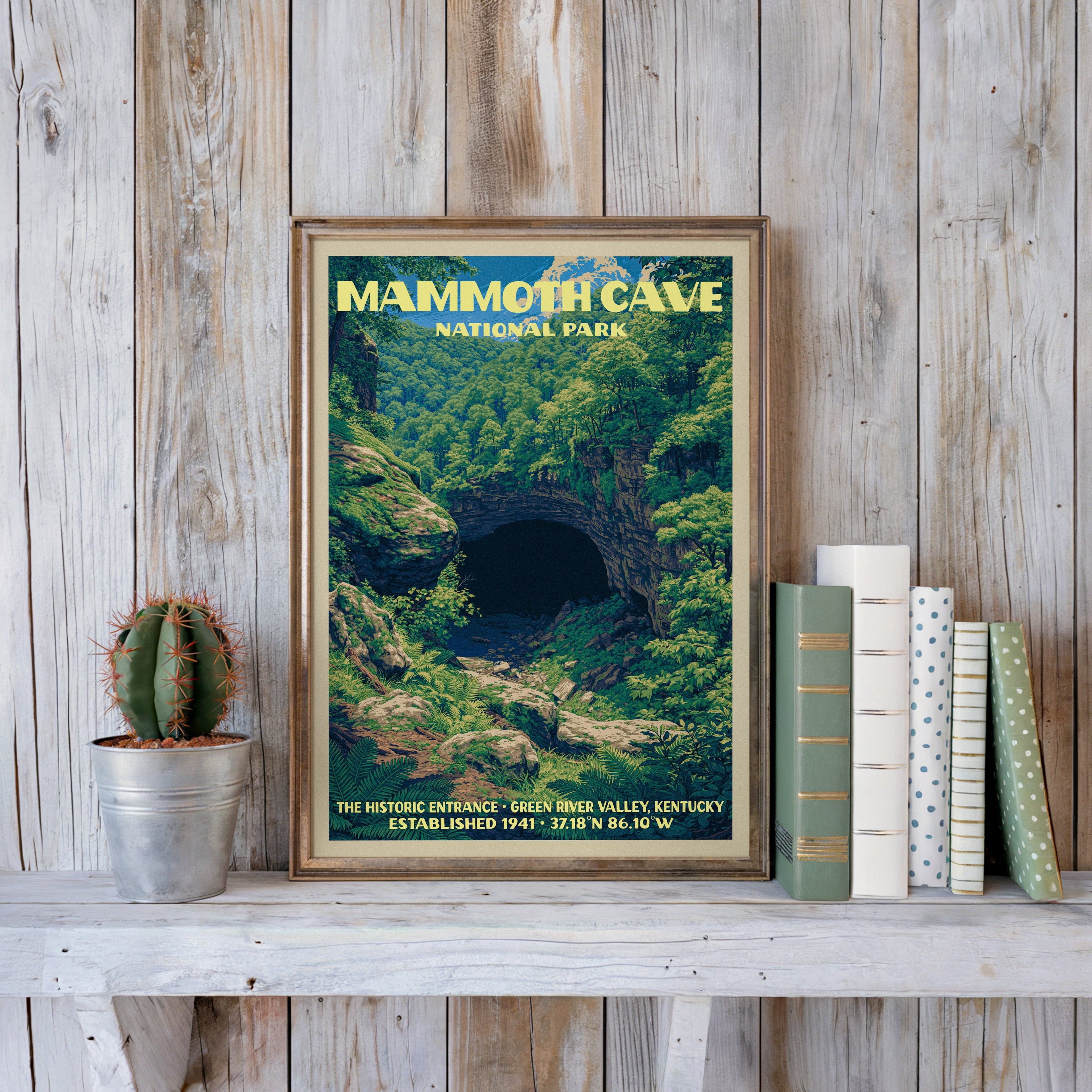 Mammoth Cave vintage poster in a slim gold frame on a whitewashed plank wall beside a cactus and pastel books