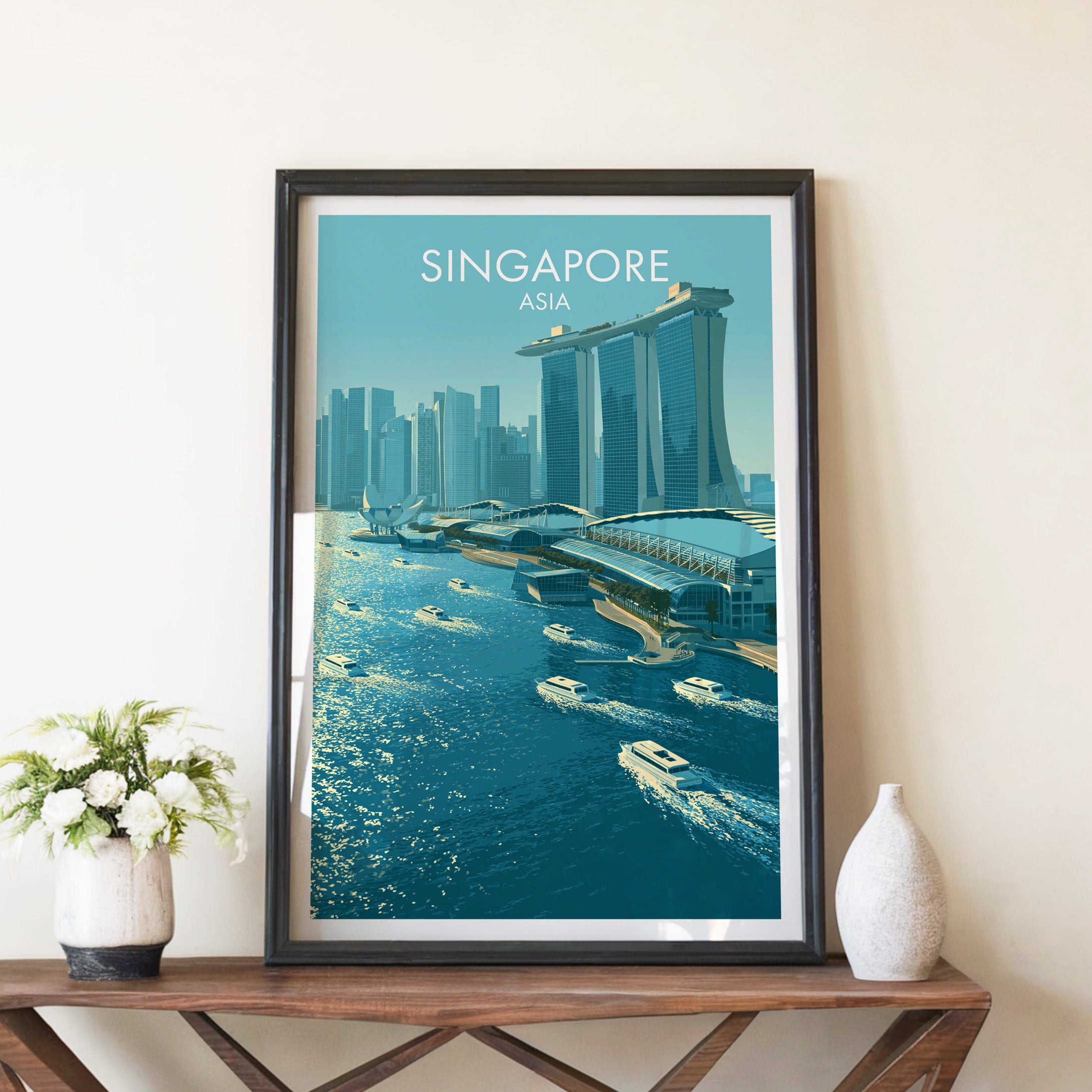 Marina Bay Sands Singapore travel poster in a black frame on a wooden console table with white flowers