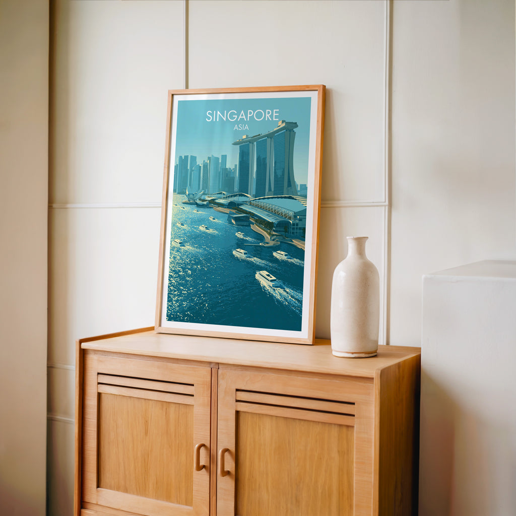 Small Marina Bay Sands Singapore travel poster in an oak frame on a mid-century sideboard with a ceramic vase