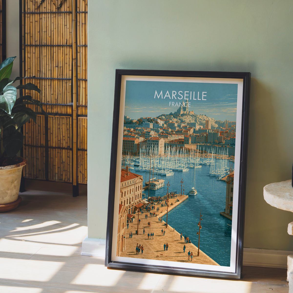Marseille France poster, dark frame leaning on a sage-green wall beside a bamboo screen and a peace lily