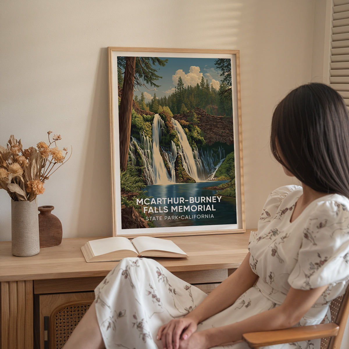 A woman in white sits beside the oak-framed McArthur-Burney Falls print on a wood sideboard