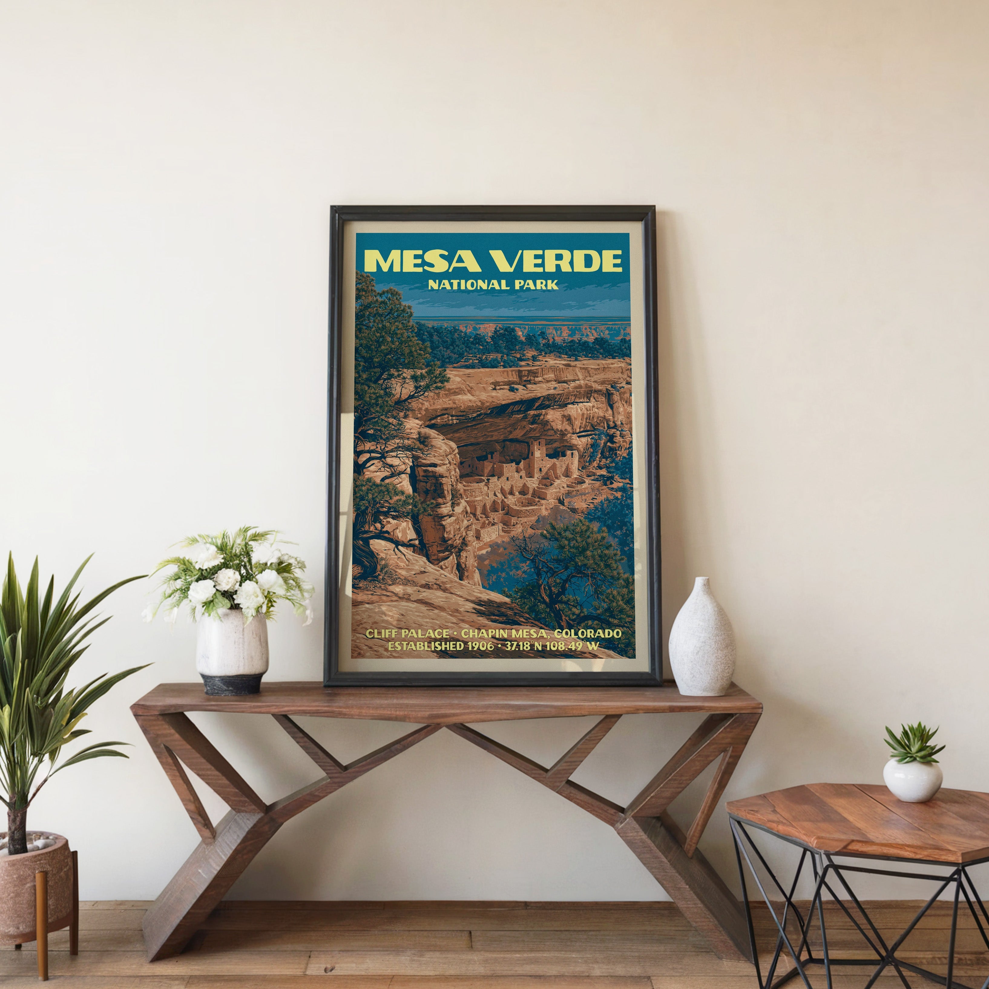Mesa Verde Cliff Palace wall art in black, leaning on a walnut console with white anemones and a vase
