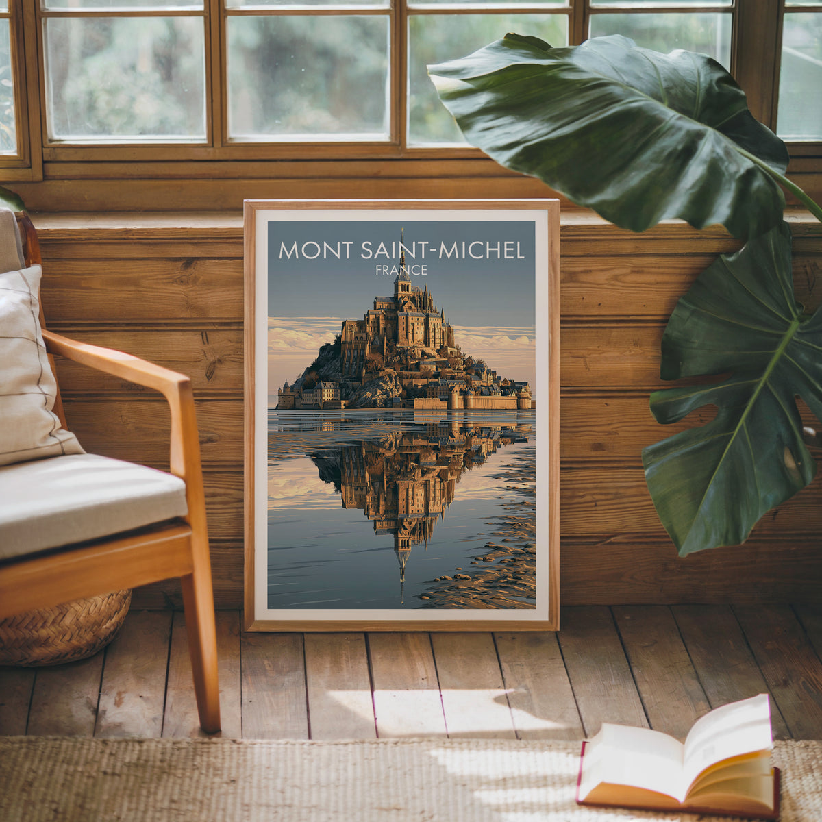 Mont Saint-Michel print leaning on a wood panelled sunroom wall with a monstera and an armchair