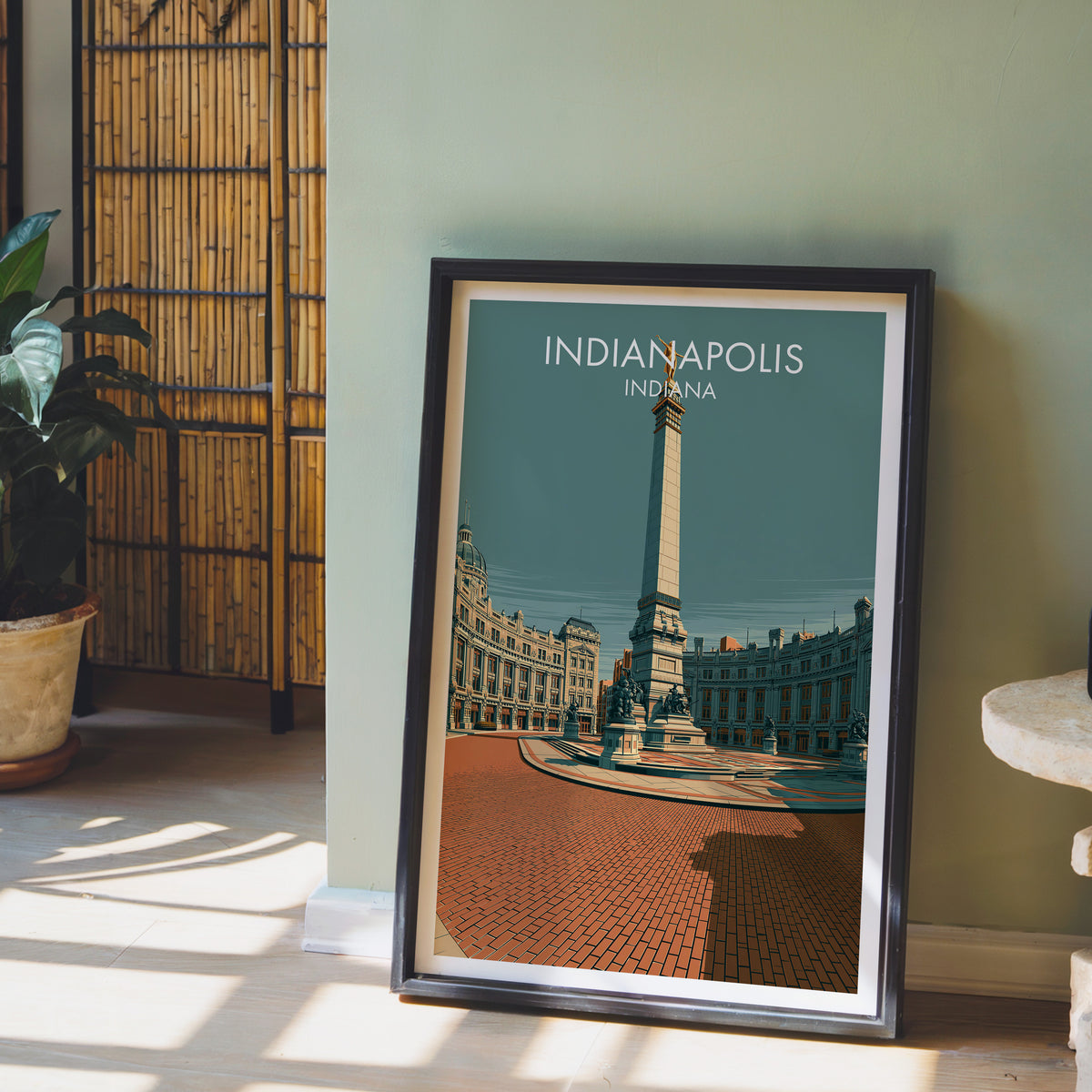 Indianapolis monument print in a black frame on a sage wall with a bamboo screen and a potted orchid.