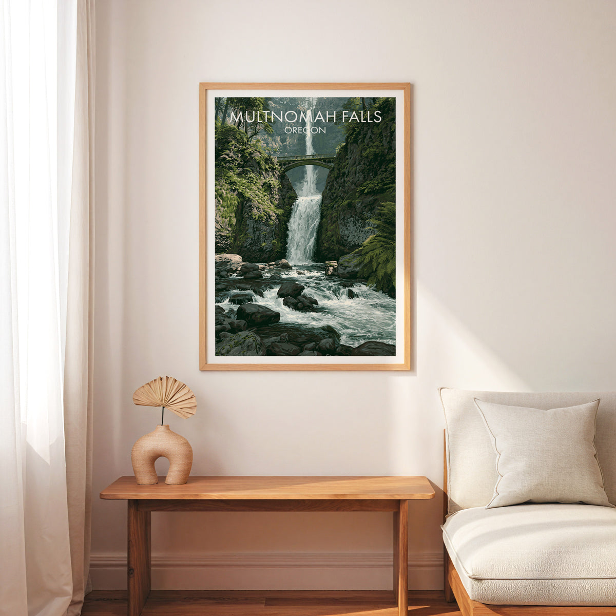 Columbia Gorge waterfall print in an oak frame above a wood bench, cream armchair and linen curtain.