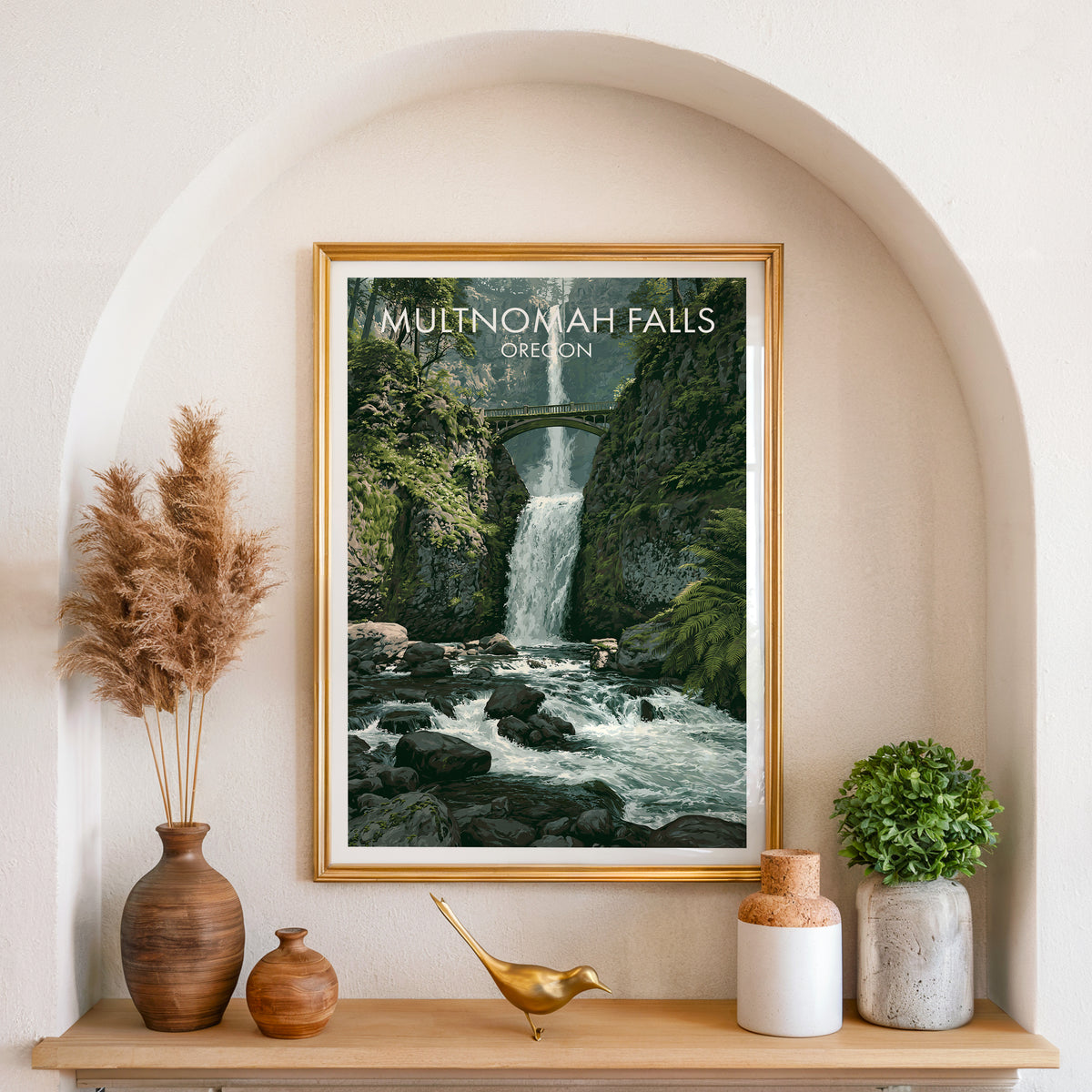 Multnomah Falls wall art in a gold frame inside an arched alcove with pampas grass and a brass bird.