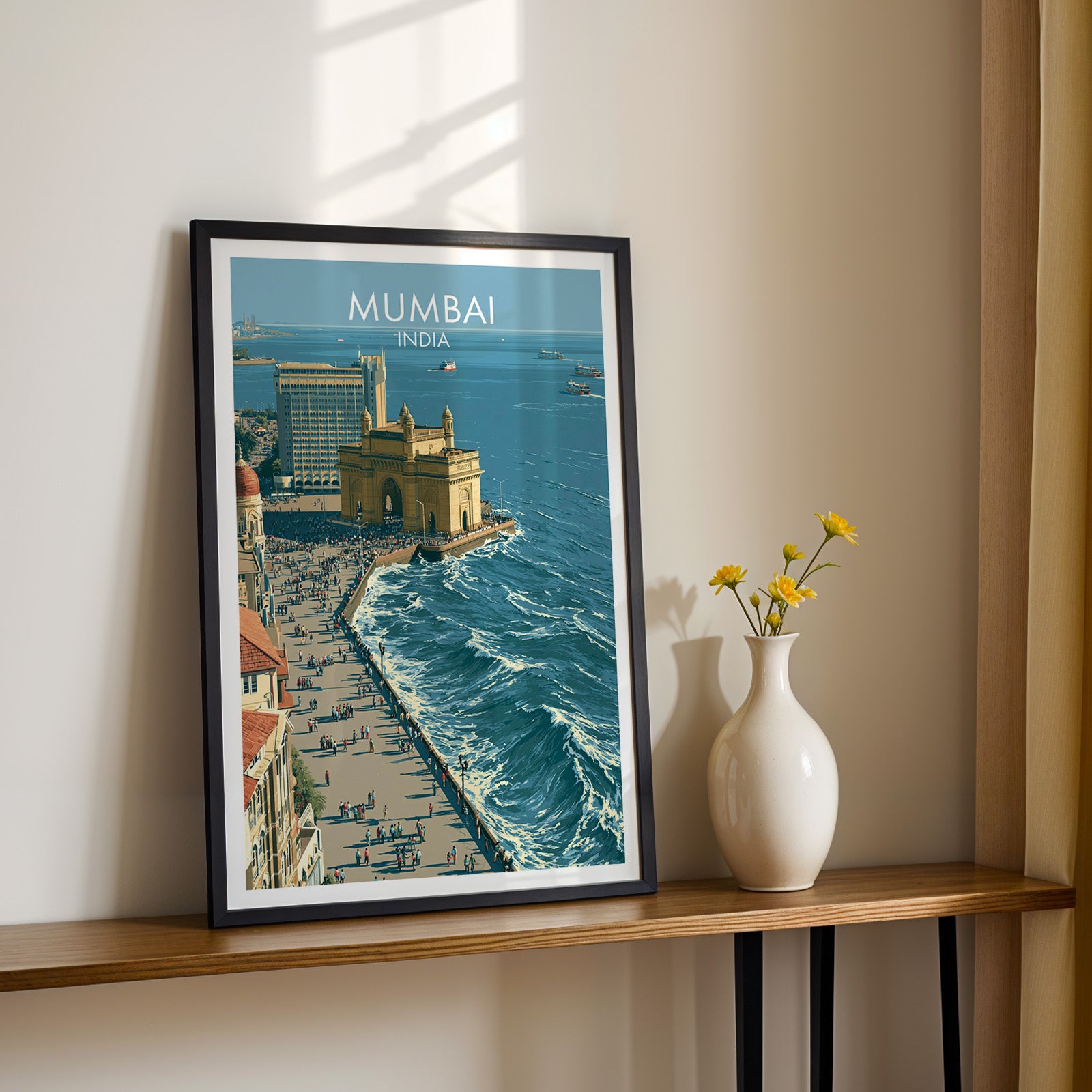 Black framed Mumbai India print on a narrow hallway console in sunlight, styled with yellow flowers