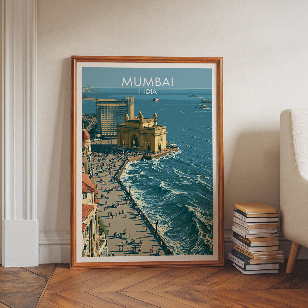India travel poster in a walnut frame leaning on a herringbone floor beside a stack of books