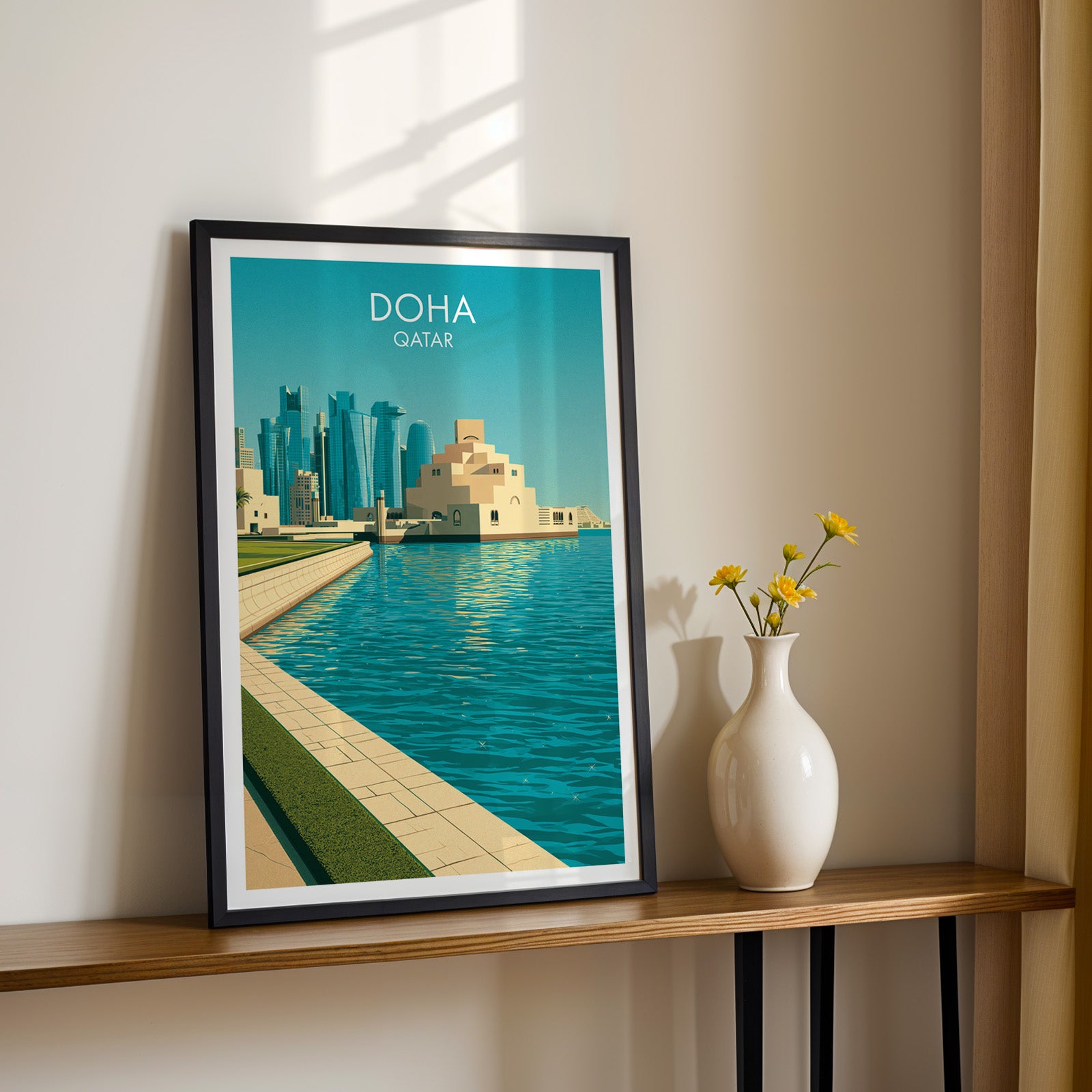 Black framed Doha Qatar print on a narrow hallway console in sunlight, styled with yellow flowers