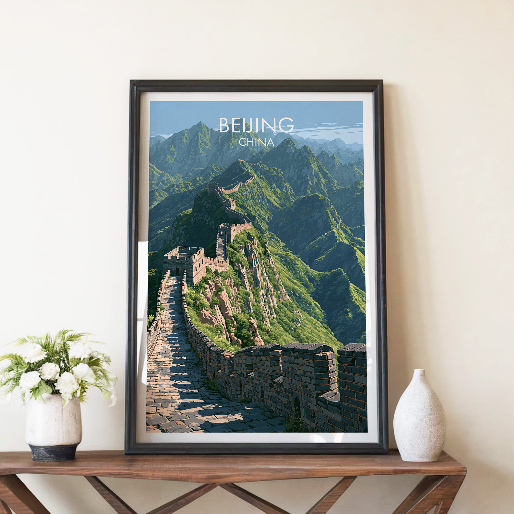 Great Wall of China Beijing travel poster in a black frame on a wooden console table with white flowers