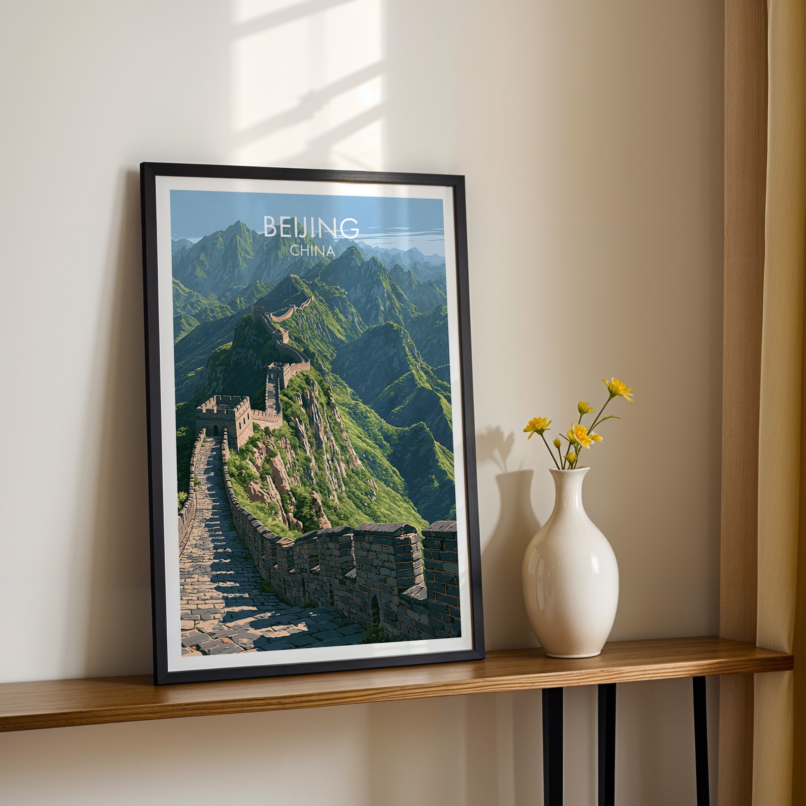 Black framed Great Wall of China Beijing print on a narrow hallway console in sunlight, styled with yellow flowers
