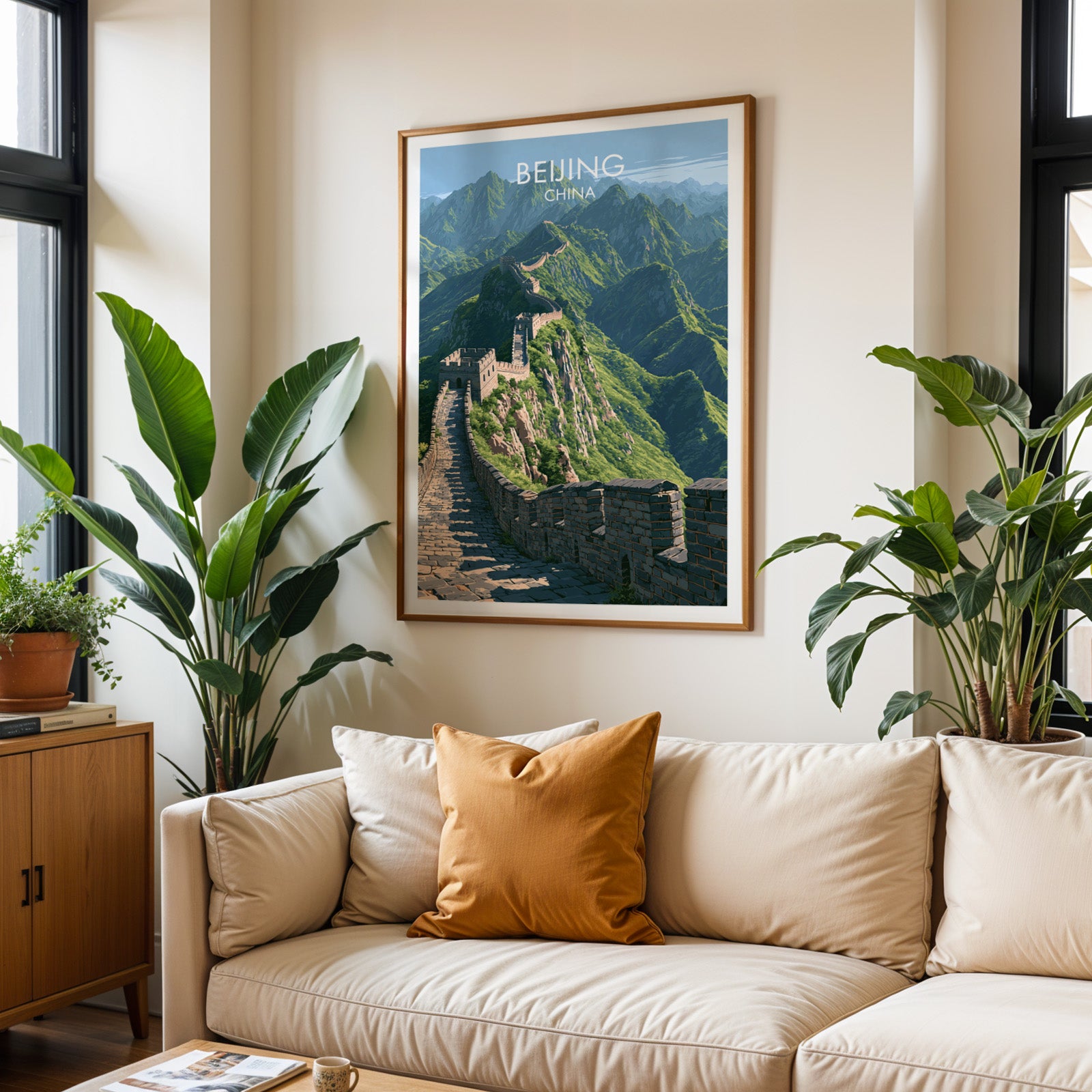 Framed Great Wall of China Beijing wall art hanging above a cream sofa in a bright living room with tropical plants