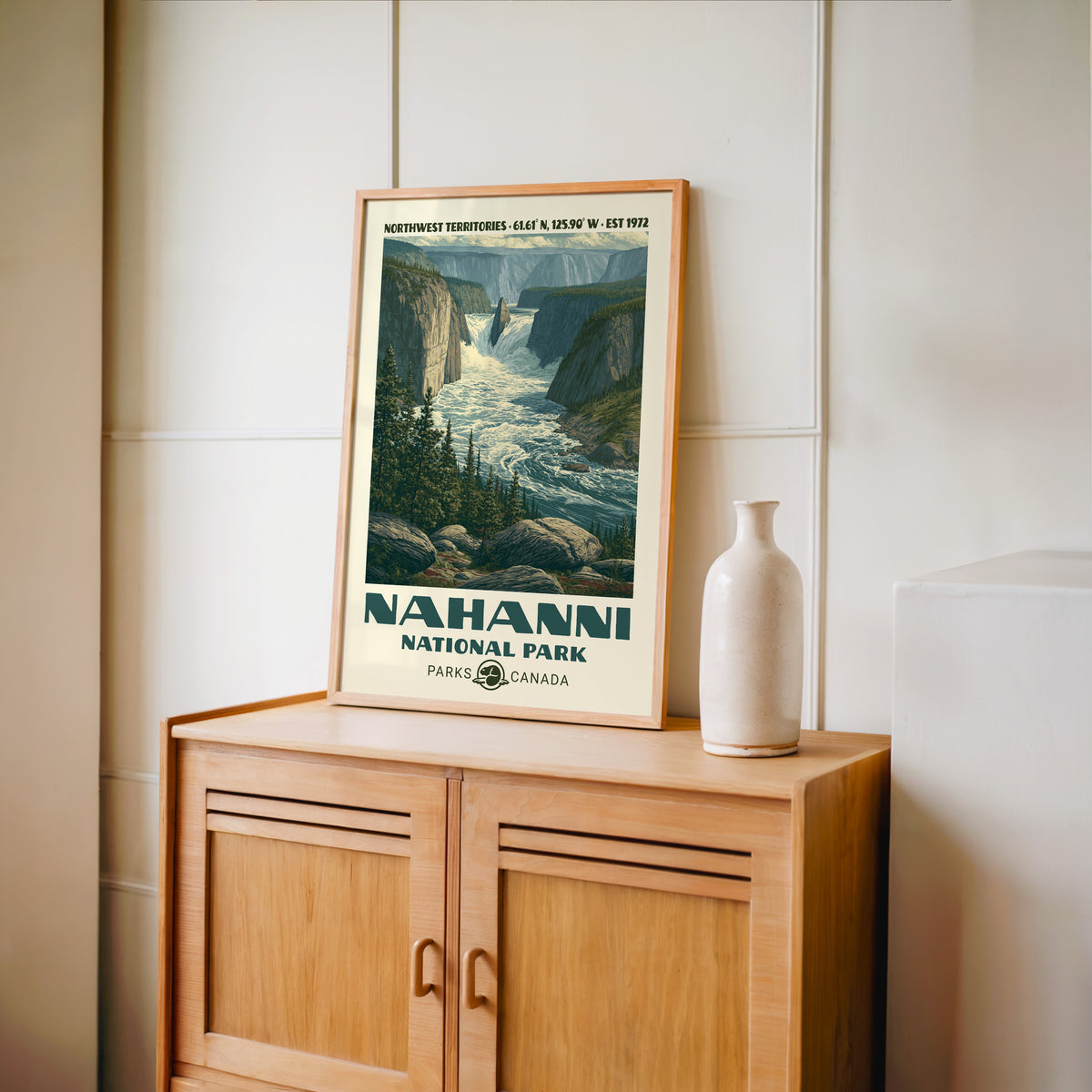 South Nahanni canyon wall art in an oak frame on a light wood cabinet beside a stoneware vase