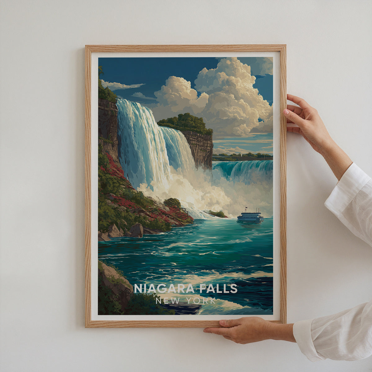 A pair of hands presenting an oak-framed Niagara Falls print on a white wall
