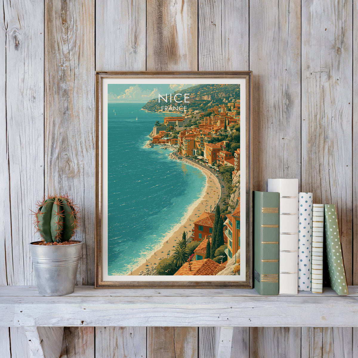 Nice French Riviera poster in a weathered frame on a whitewashed plank shelf with a cactus and books