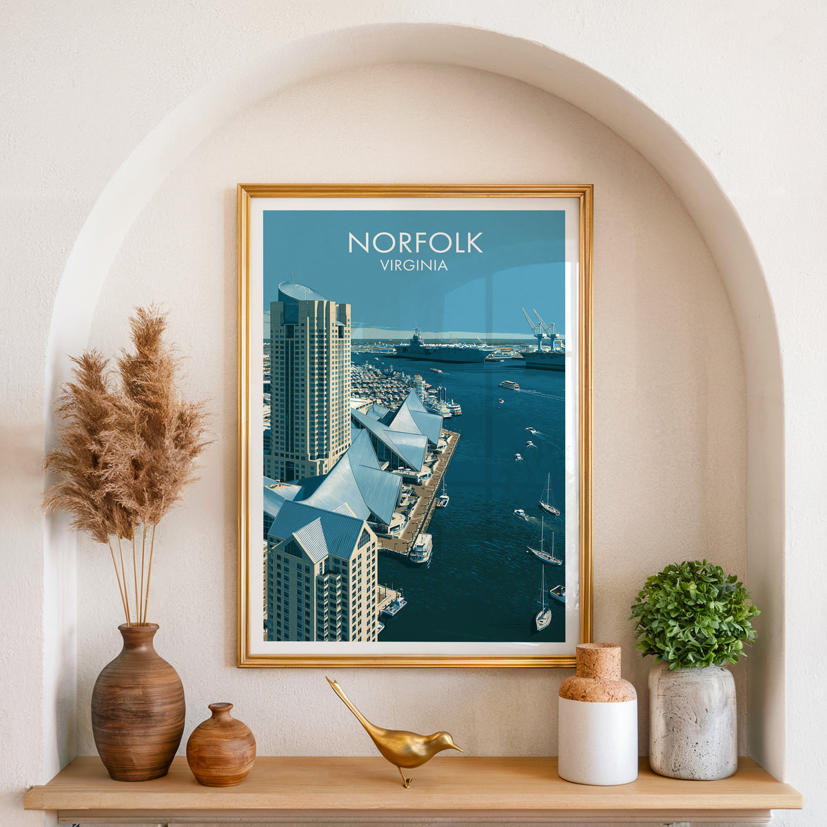 Norfolk Virginia travel print in a gold frame set in an arched alcove with pampas grass and a brass bird