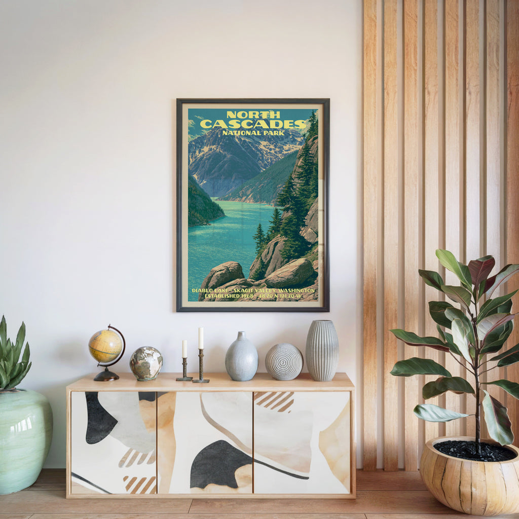 North Cascades National Park poster in a black frame above a light wood sideboard by a slatted wall panel