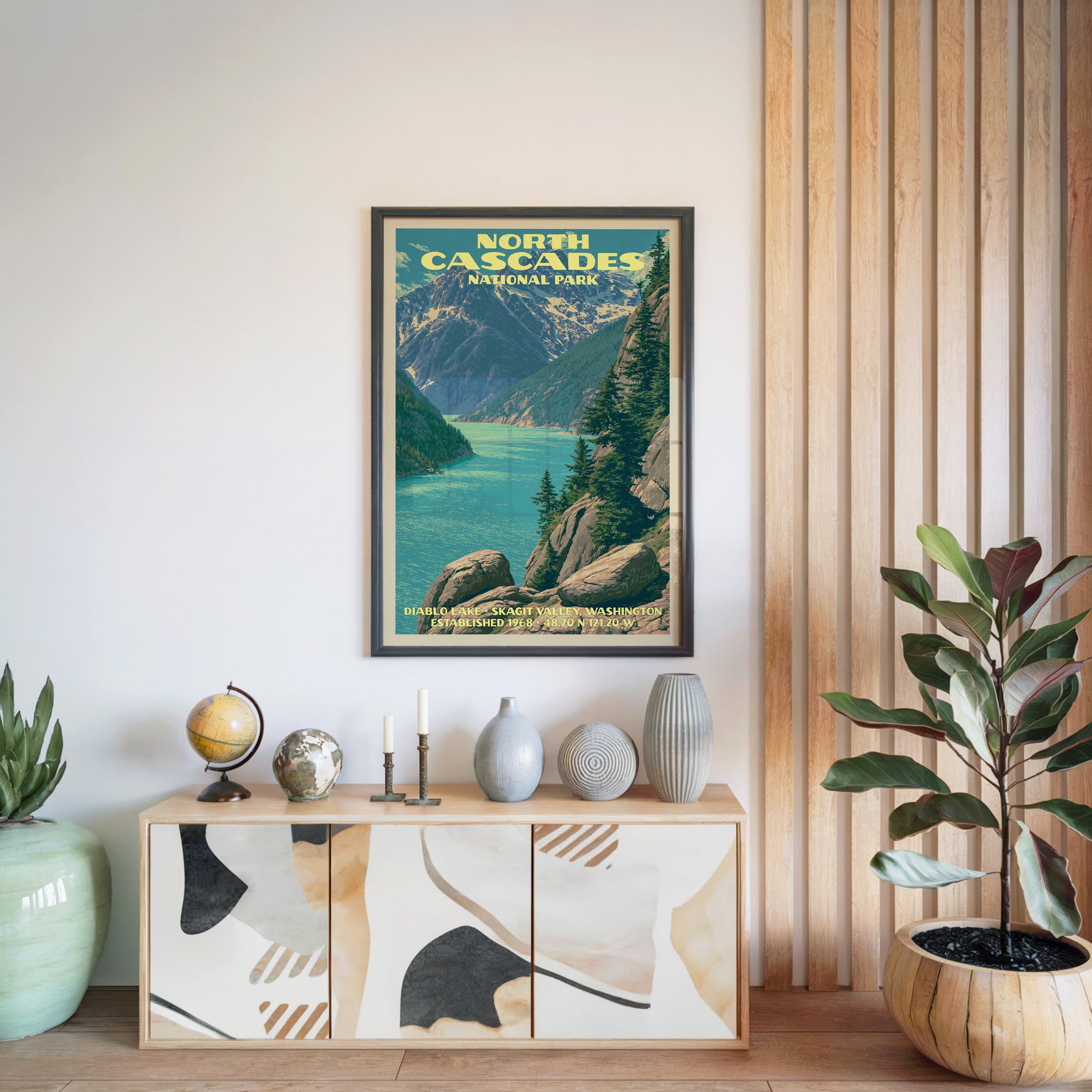 North Cascades National Park poster in a black frame above a light wood sideboard by a slatted wall panel