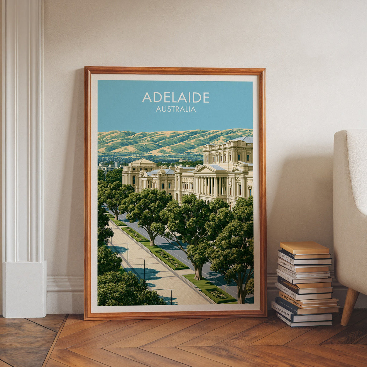 South Australia artwork in a walnut frame on herringbone floor beside book stacks and a pale armchair