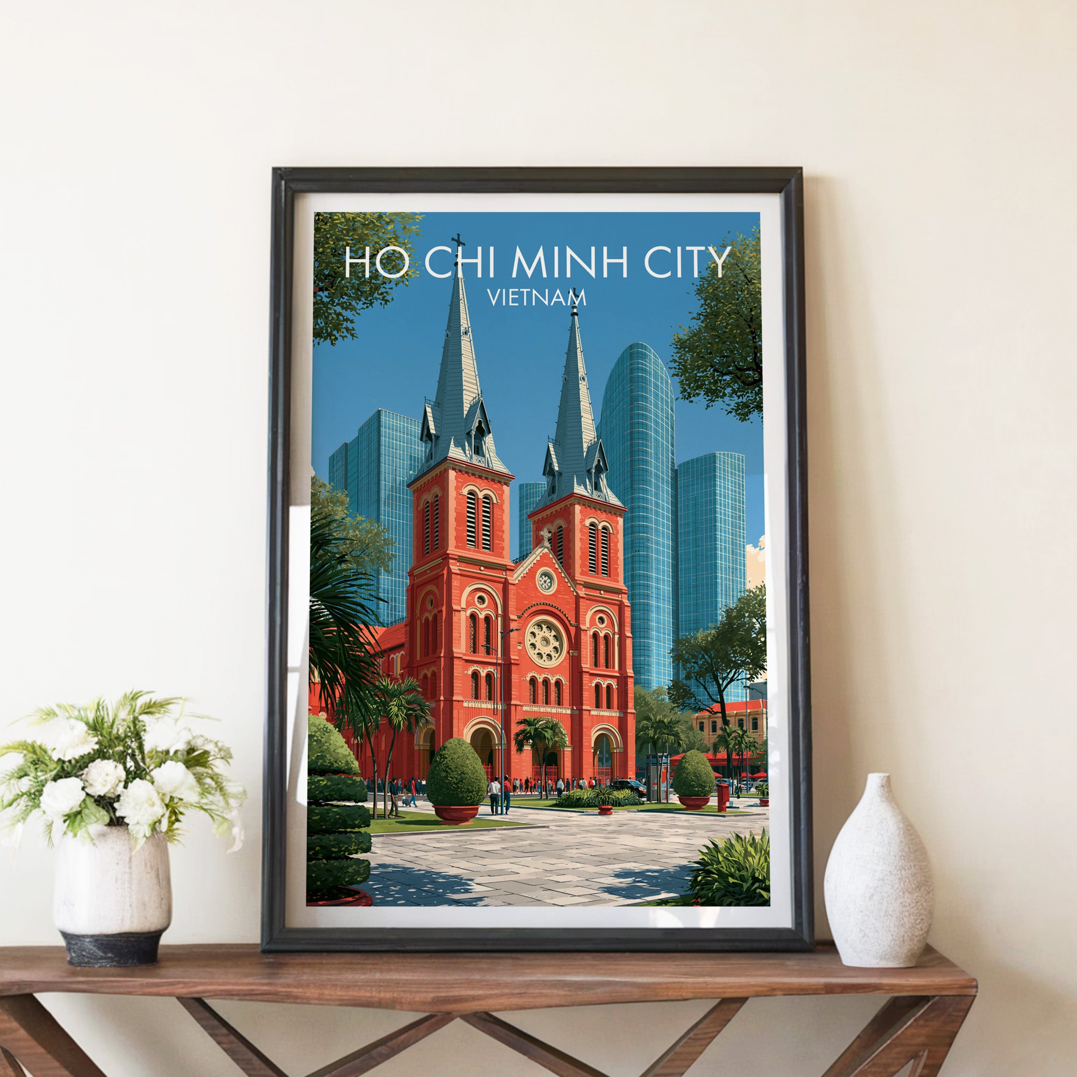 Ho Chi Minh City Vietnam travel poster in a black frame on a wooden console table with white flowers