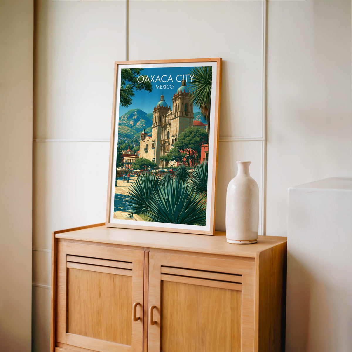Plaza and church artwork in an oak frame on a light oak cabinet against a cream panelled wall