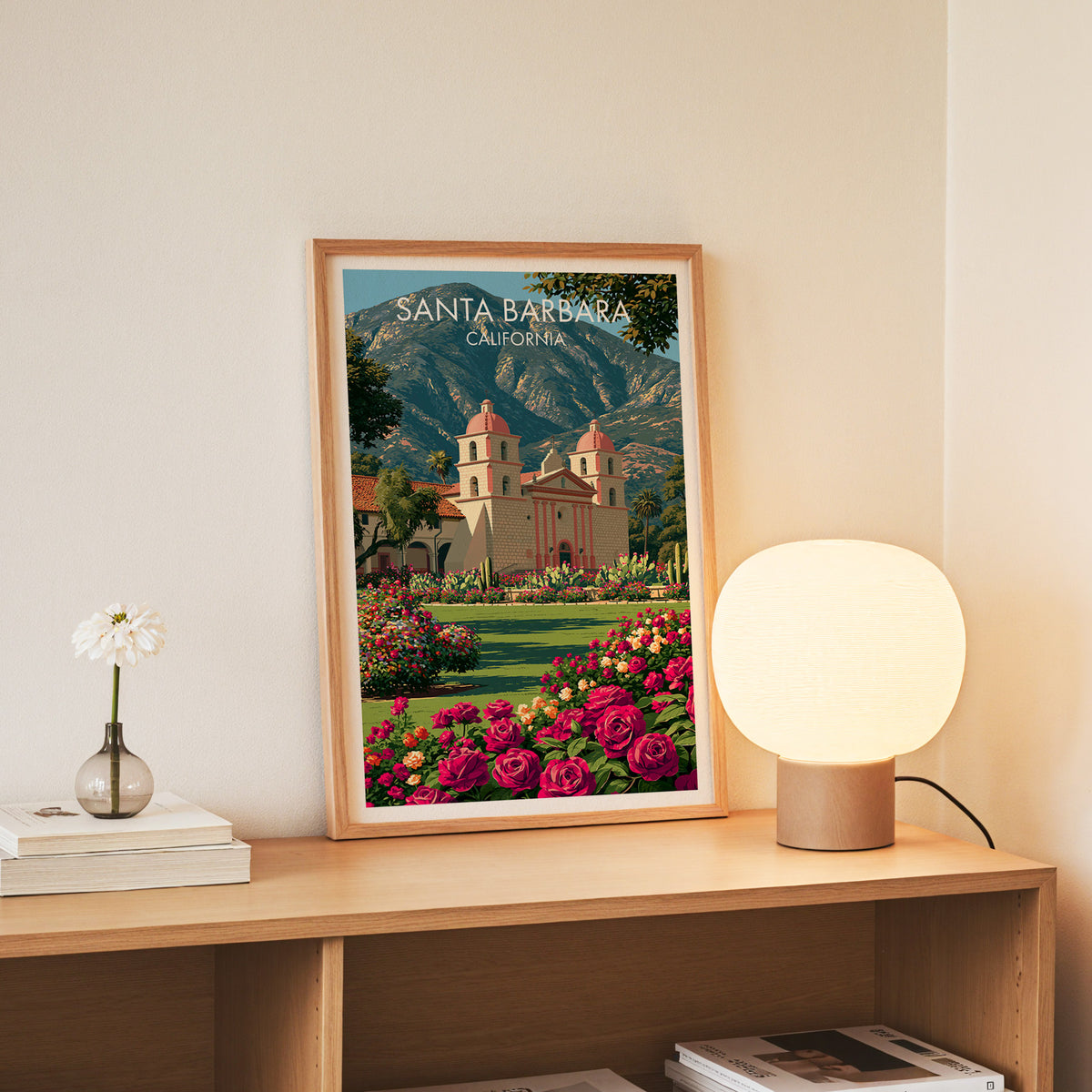 Old Mission print in a slim oak frame standing on an oak console beside white daisies in a glass jar.