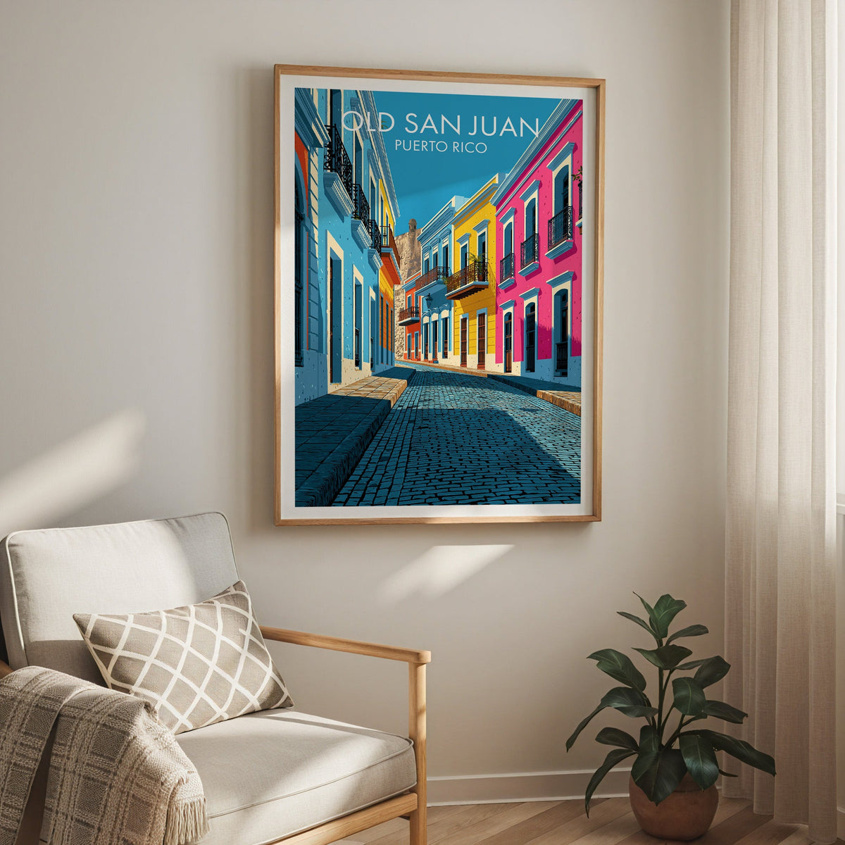 Colourful old town scene in an oak frame above a cream armchair with a check cushion and a sheer curtain