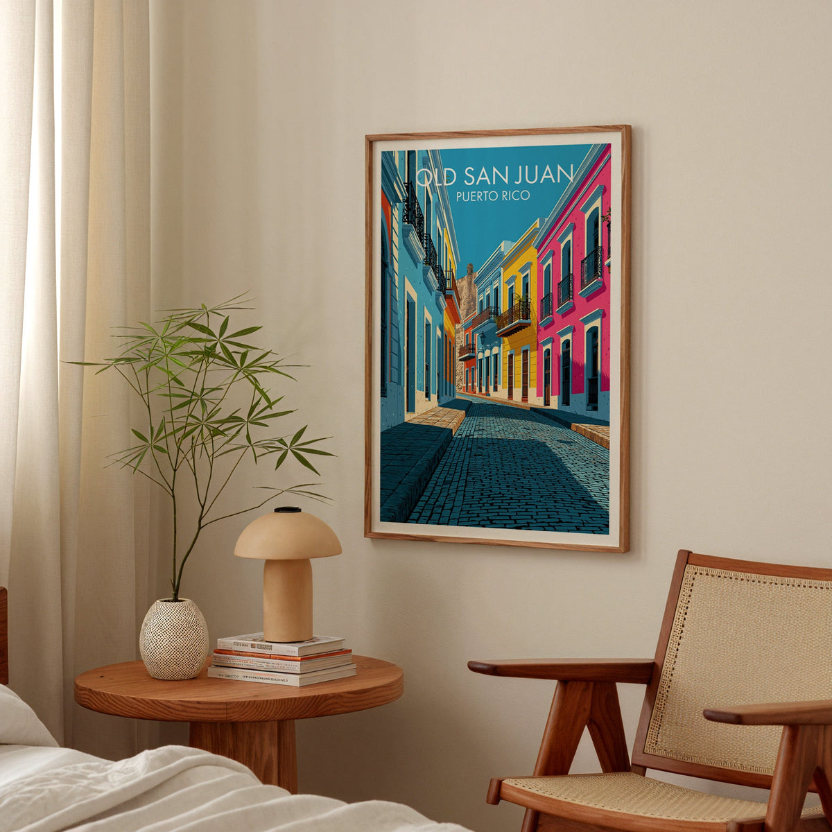 Pink and cyan street print in an oak frame in a bedroom above a round table with a mushroom lamp and bamboo