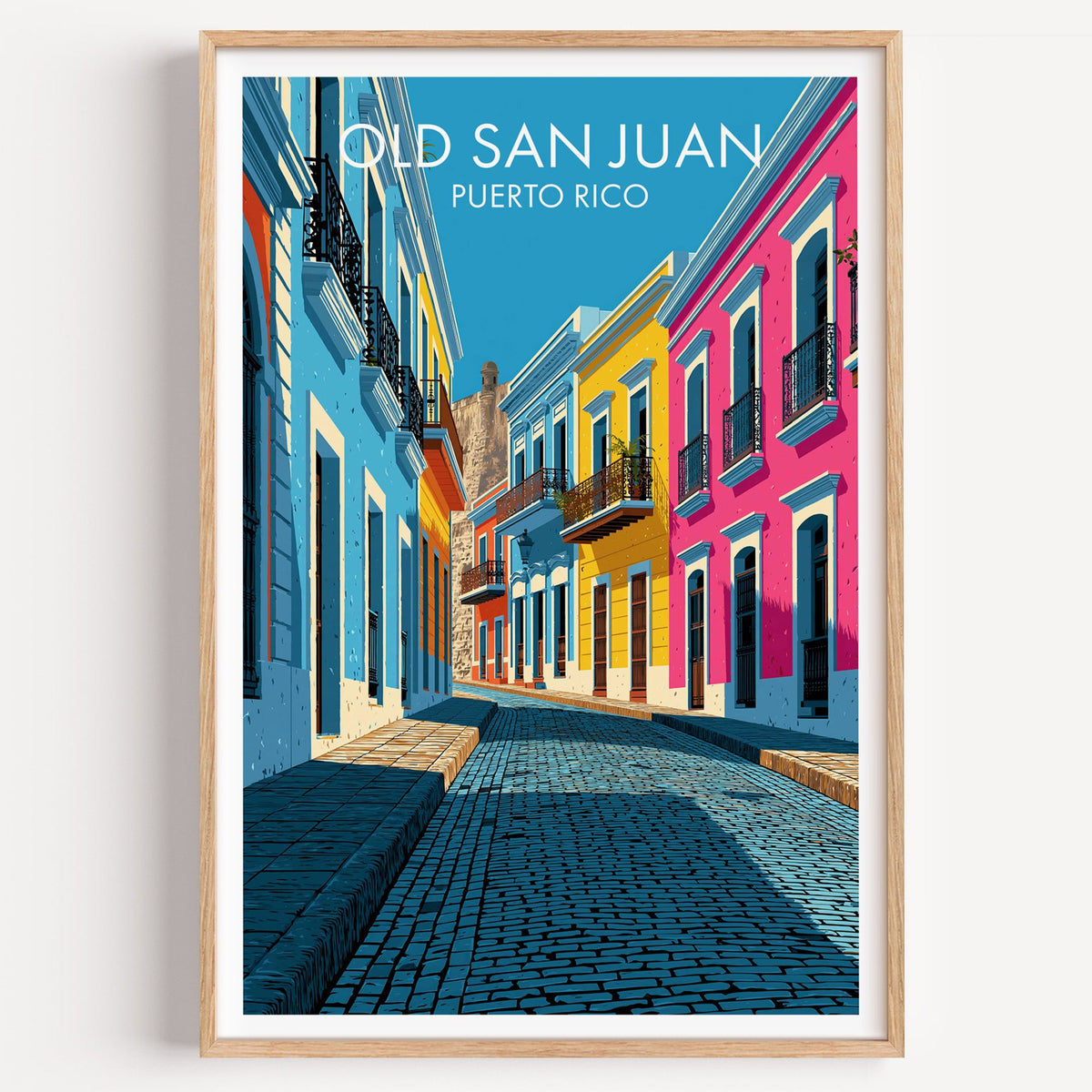 Old San Juan blue cobblestone street print in a light oak frame on a plain white wall