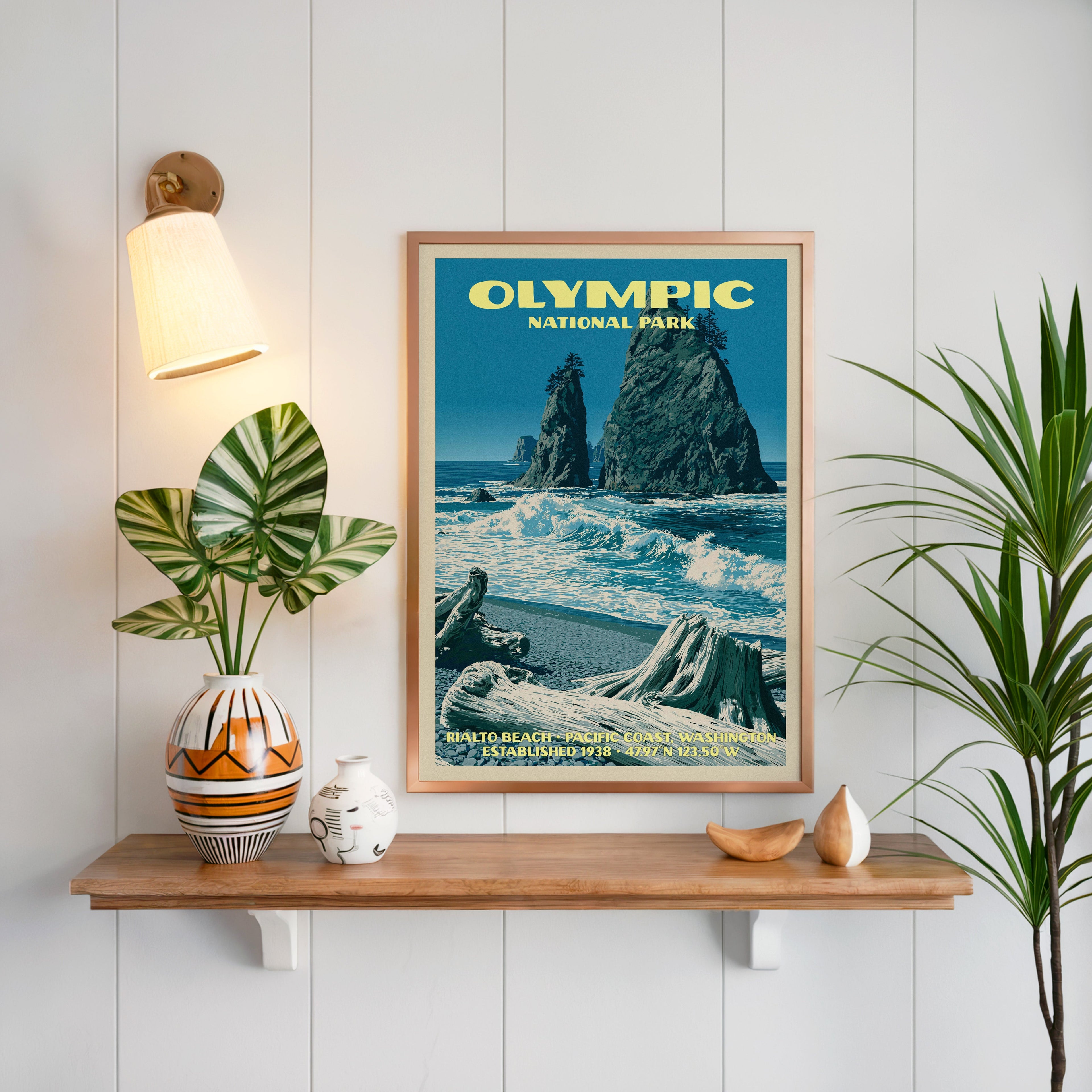 Rialto Beach Olympic print framed on white panelling above an oak shelf with a patterned vase and brass sconce