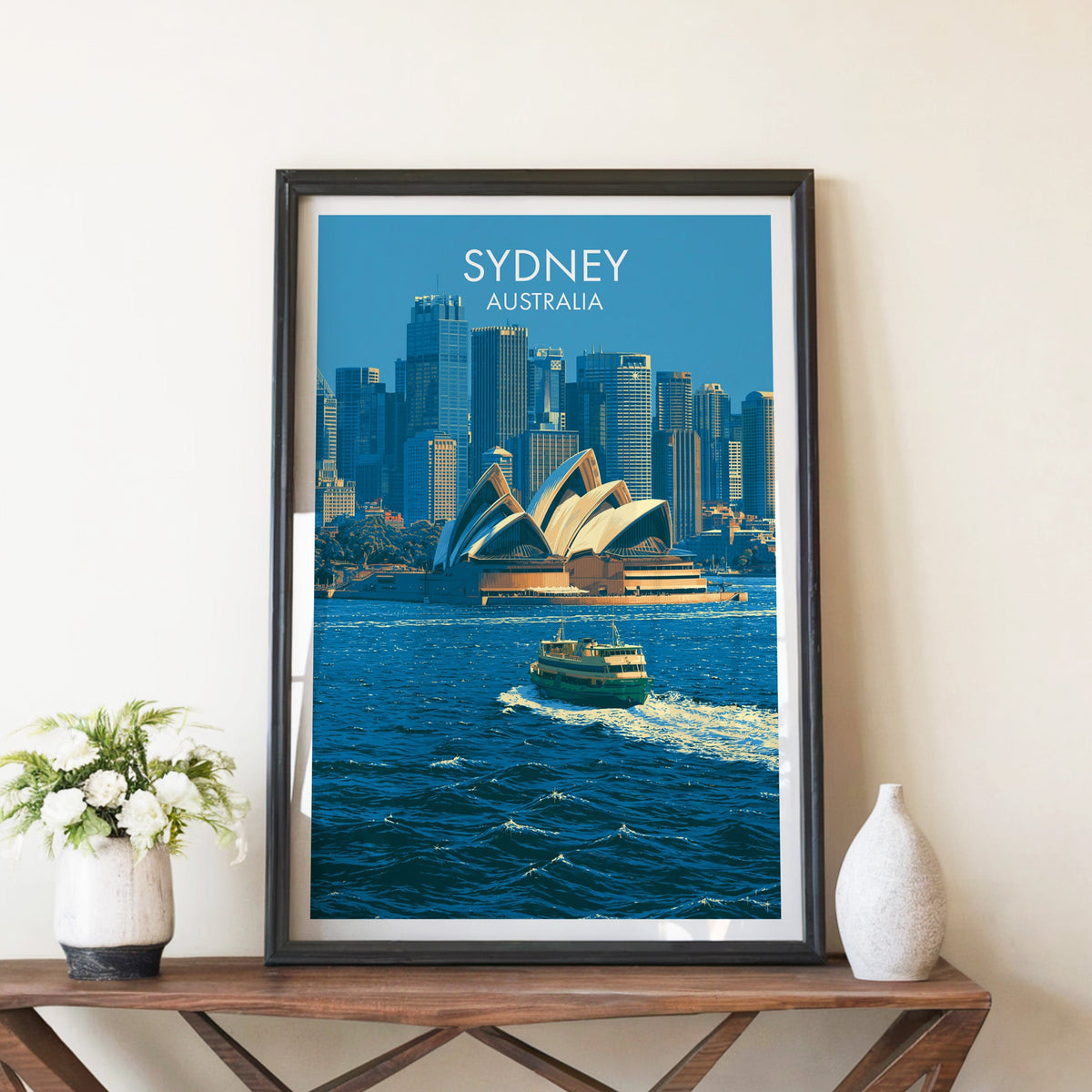 Sydney harbour poster in a black frame on a walnut console with white peonies and a stone vase
