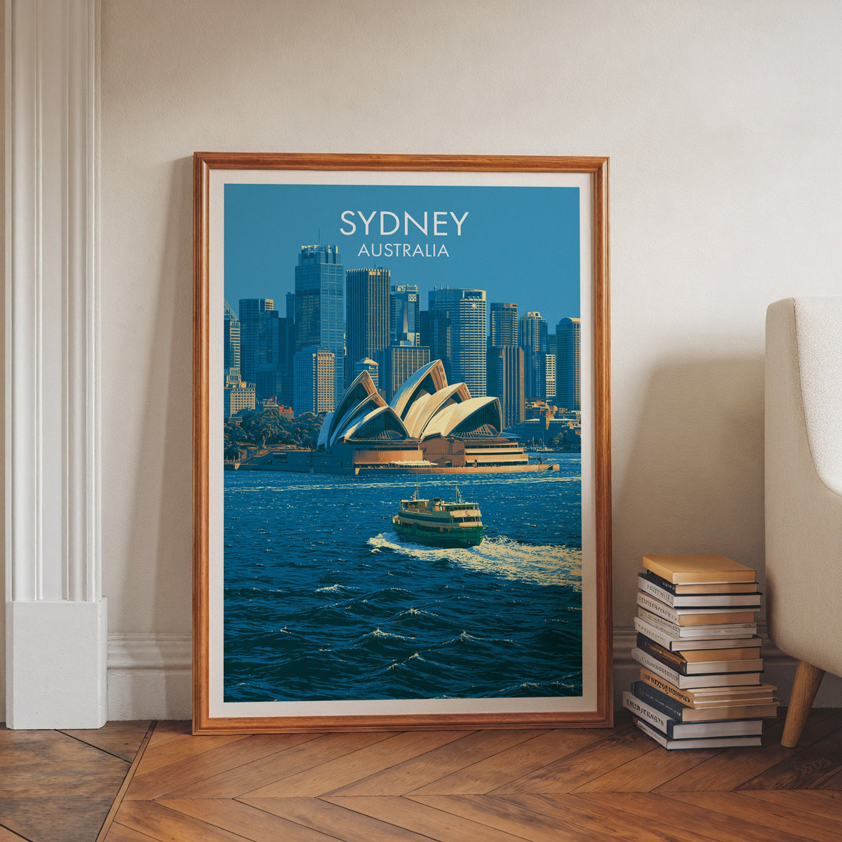Sydney city print in a walnut frame on herringbone floor beside stacked books and a pale armchair