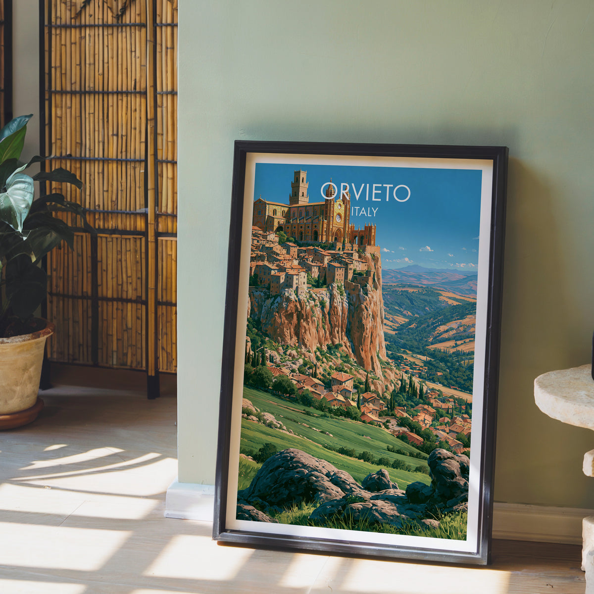 Orvieto tufa plateau poster, dark frame leaning on a sage-green wall beside a bamboo screen and a peace lily