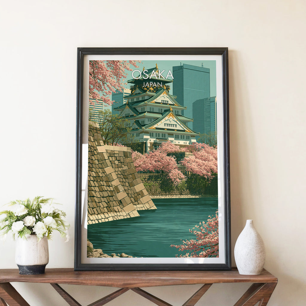Osaka Castle Japan travel poster in a black frame on a wooden console table with white flowers