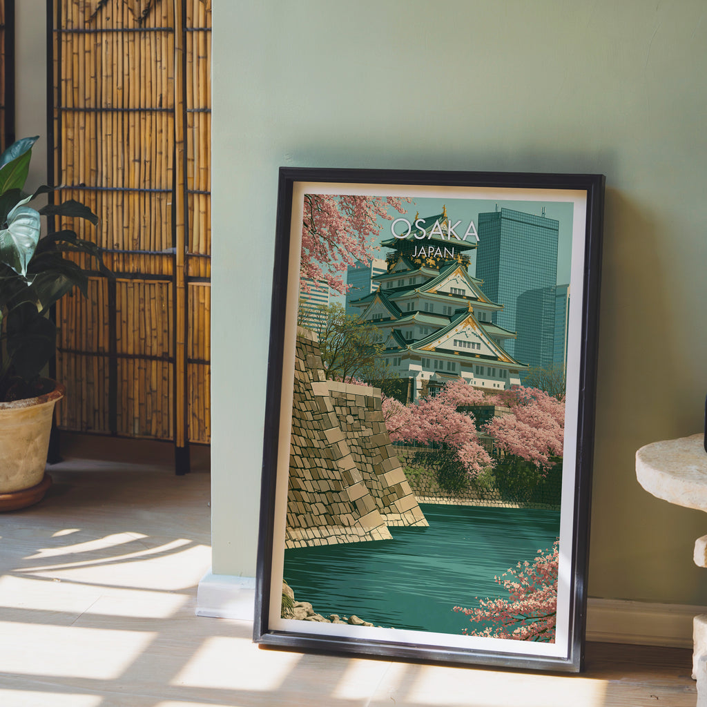 Osaka Castle Japan wall art in a black frame leaning against a sage green wall beside a bamboo screen