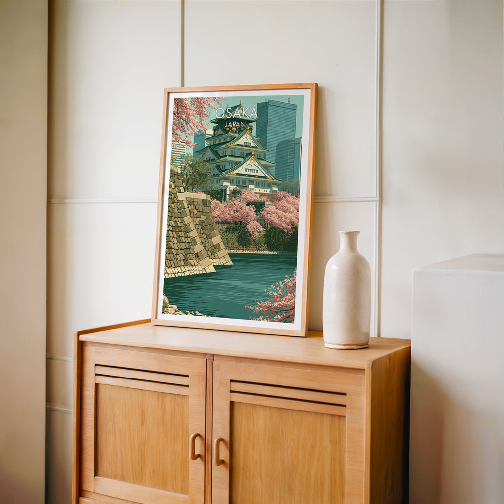 Small Osaka Castle Japan travel poster in an oak frame on a mid-century sideboard with a ceramic vase